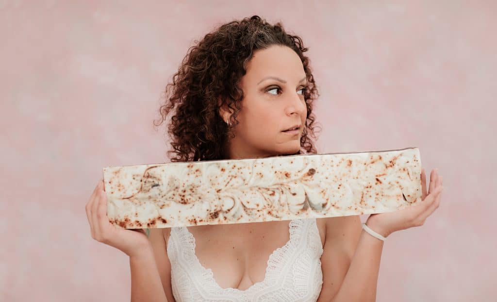 Founder & Product Artisan Raquel Garza González holds an uncut block of Oatmeal soap.